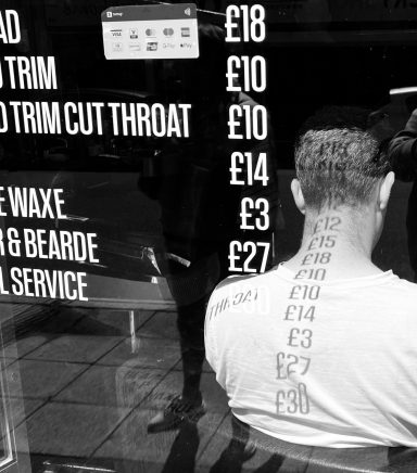 Find a photograph of a man sitting in a barbers window for sale.