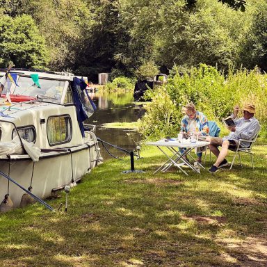 Moored up Find a photograph of a boat moored up on the canal, with people on the shore.