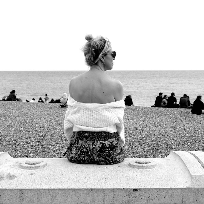 Lost in thought Black and white photograph of woman sitting on a sea wall.