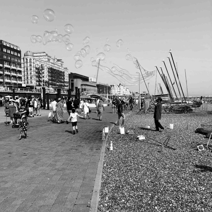 Lots of bubbles Black and white photograph of man making bubbles on Brighton beach.