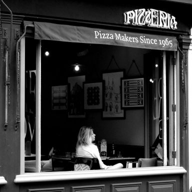 Find a photograph of a young woman sitting in a restaurant waiting.