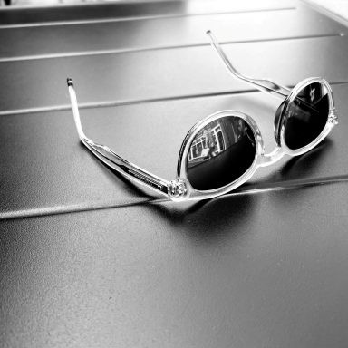 Find a black and white photograph of a pair of sunglasses on a coffee table. Street photography.