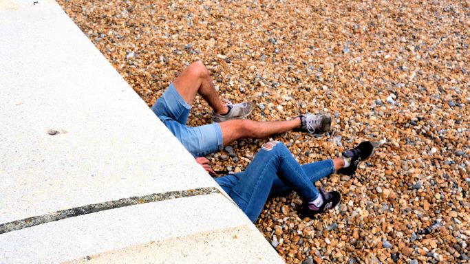 Find photograph of couple lying down on Brighton Beach. 