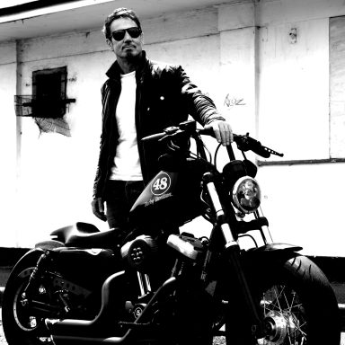 Photograph of a man standing by his Harley Davidson motorbike